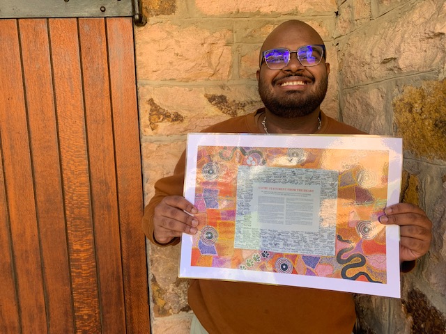 Aaron Vidyasager holding a copy of the Uluru Statement From the Heart
