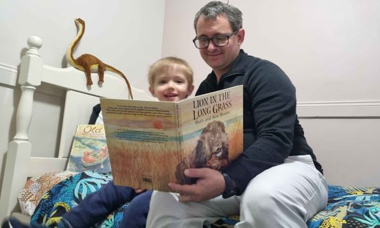 The Rev'd Andrew Schmidt and son John reading Lion in The Long Grass