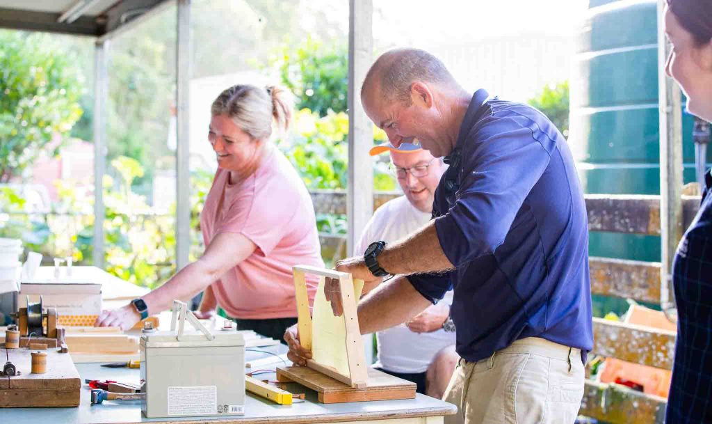 Farmer Jeff McLennan teaches workshop guests the art of handmaking wooden frames for a beehive